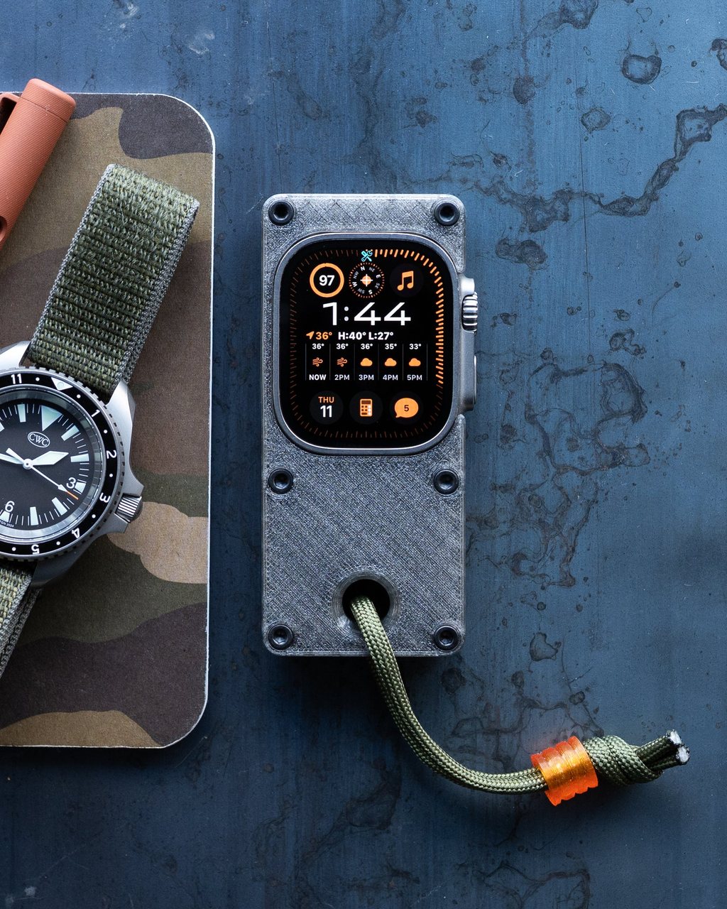 The case on a table next to a mechanical wristwatch, watch face lit