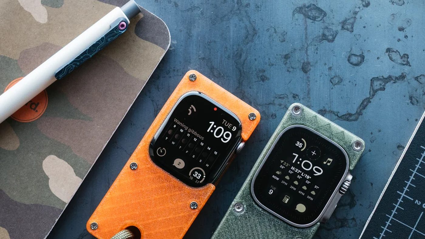 Two cases, orange and olive, lying on a cutting mat with their paracord loops