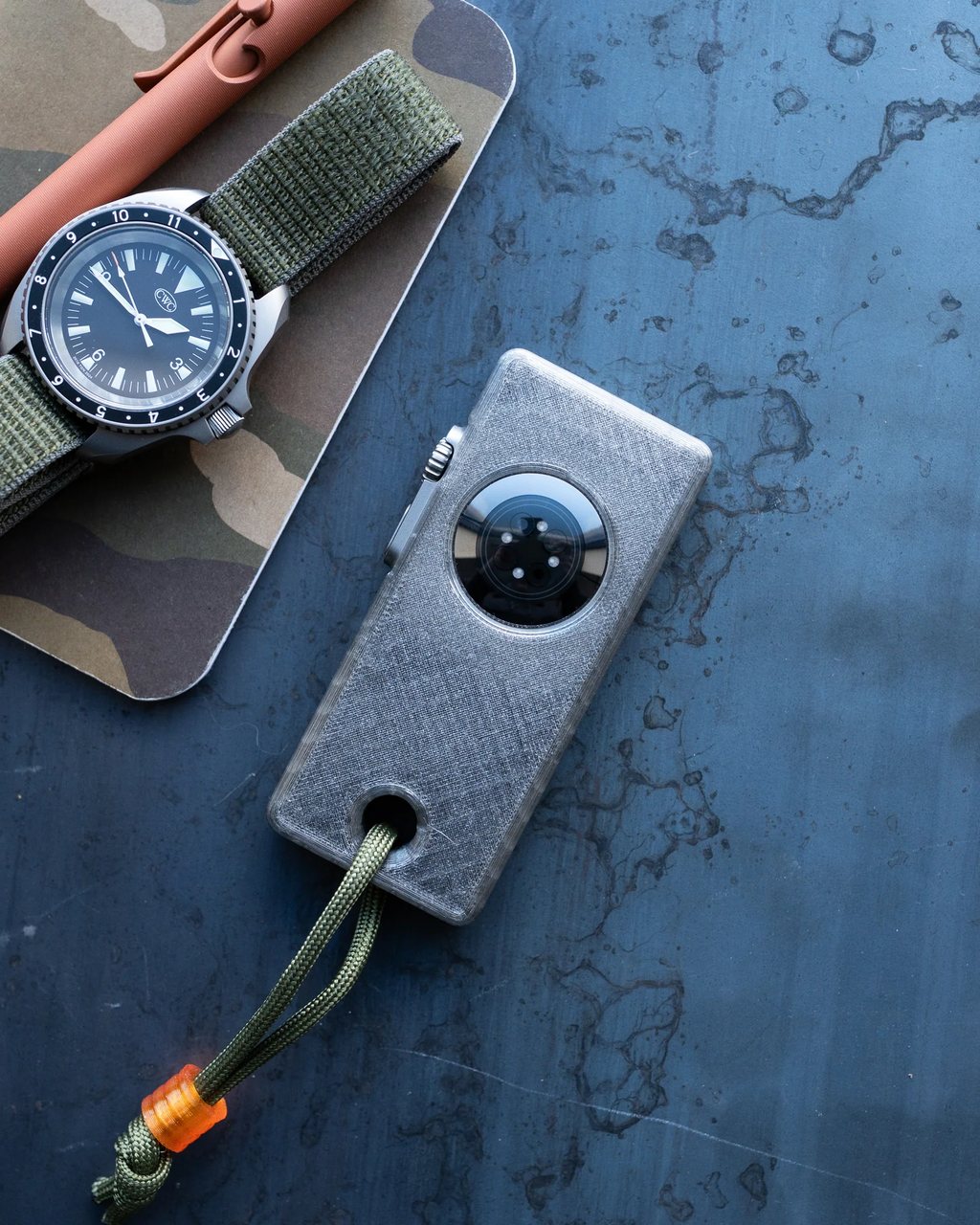 The case face down, its charging opening and the watch's sensor showing, beside a wristwatch